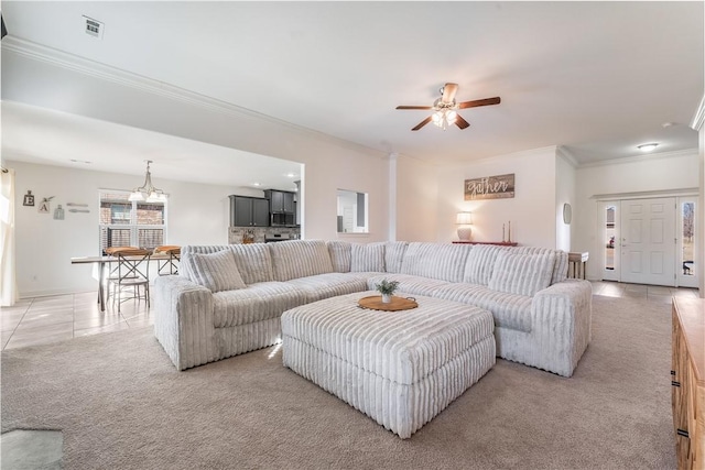 living area with light carpet, light tile patterned floors, ornamental molding, and ceiling fan with notable chandelier