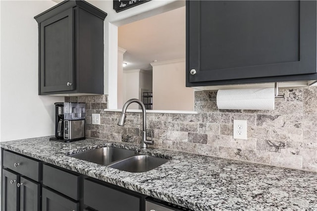 kitchen featuring ornamental molding, backsplash, stone countertops, and a sink