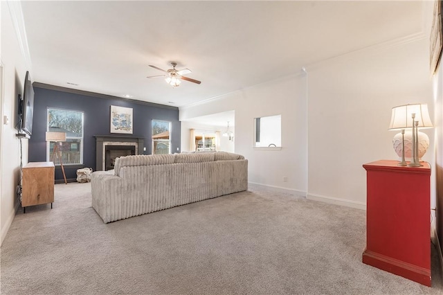 living room with a fireplace, ornamental molding, carpet flooring, baseboards, and ceiling fan with notable chandelier