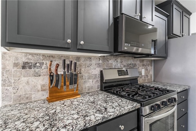 kitchen with light stone countertops, tasteful backsplash, and stainless steel range with gas stovetop