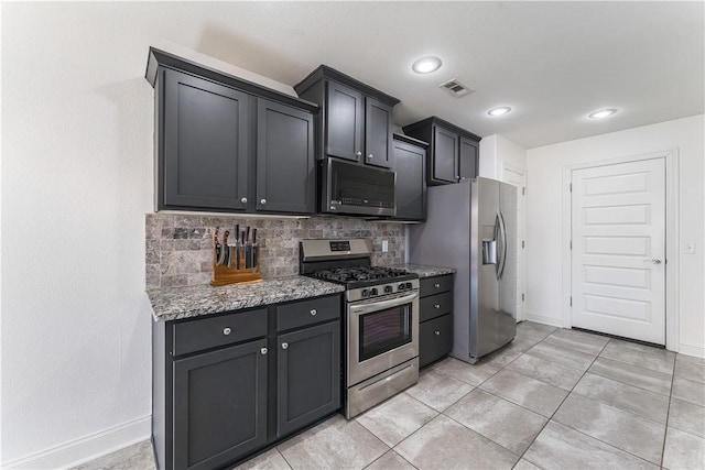 kitchen featuring stone counters, visible vents, baseboards, appliances with stainless steel finishes, and tasteful backsplash