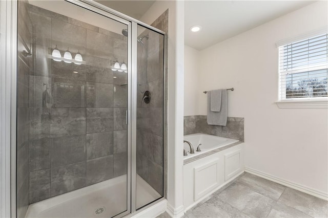 bathroom featuring a stall shower, a garden tub, and baseboards