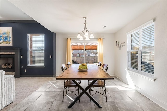 dining area featuring a fireplace, a wealth of natural light, and an inviting chandelier