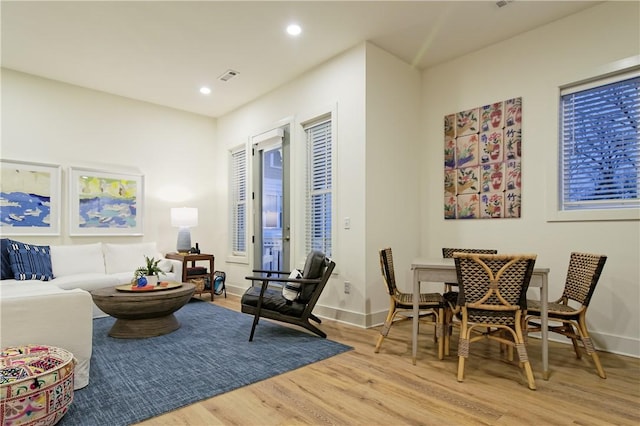 living area with baseboards, wood finished floors, visible vents, and recessed lighting