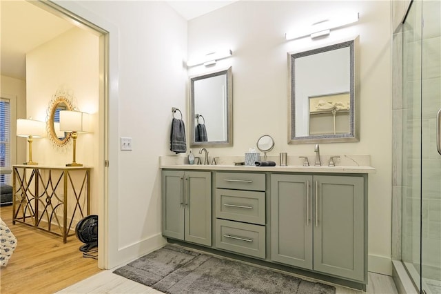 bathroom with an enclosed shower, wood finished floors, a sink, and baseboards