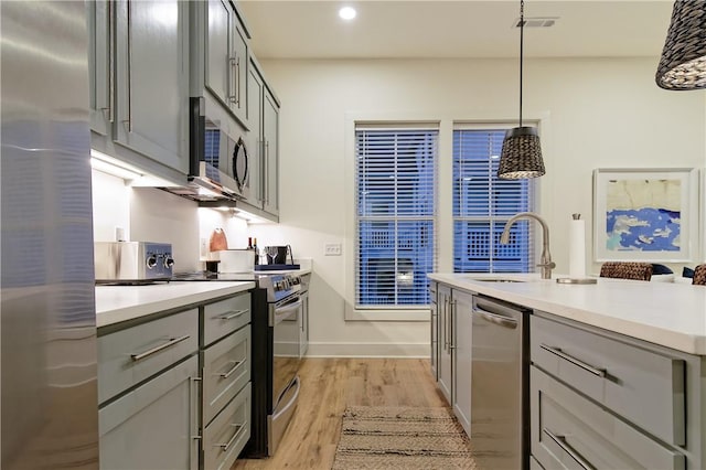 kitchen featuring stainless steel appliances, light wood finished floors, and gray cabinetry