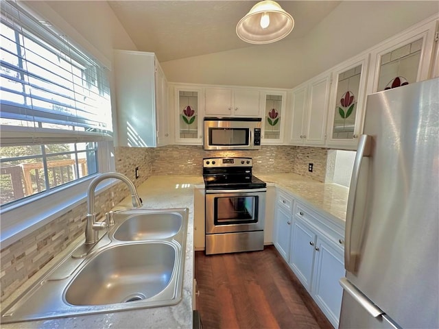 kitchen with stainless steel appliances, backsplash, glass insert cabinets, vaulted ceiling, and a sink