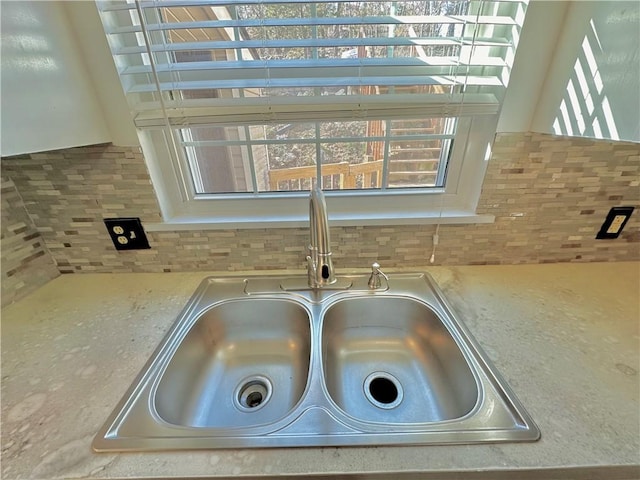 room details featuring light stone counters, a sink, and decorative backsplash