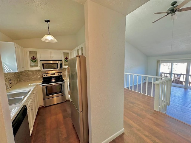 kitchen with dark wood finished floors, appliances with stainless steel finishes, white cabinets, vaulted ceiling, and a sink