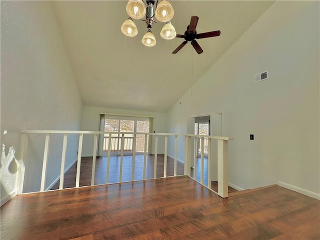 empty room featuring high vaulted ceiling, visible vents, baseboards, and wood finished floors