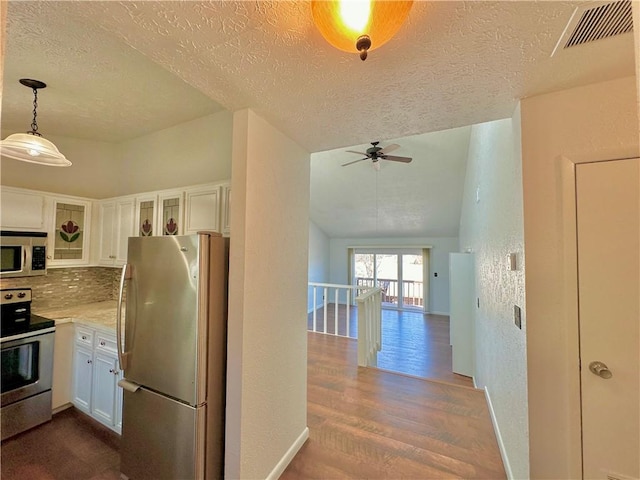 kitchen with stainless steel appliances, tasteful backsplash, visible vents, and white cabinets