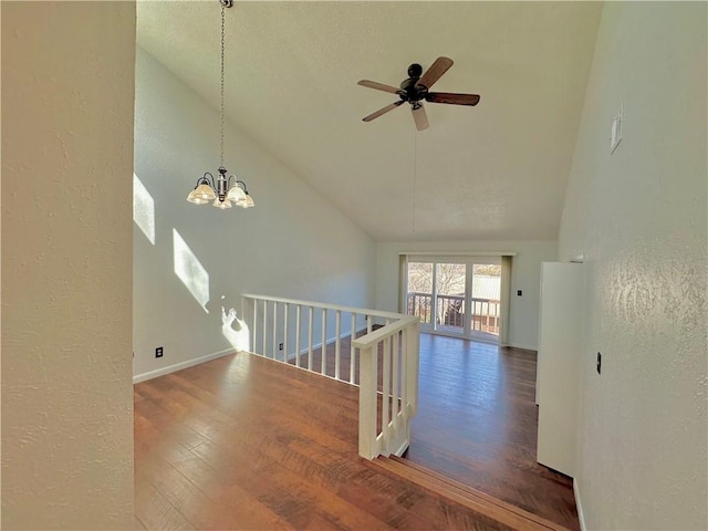 unfurnished room with high vaulted ceiling, ceiling fan with notable chandelier, a textured wall, and wood finished floors