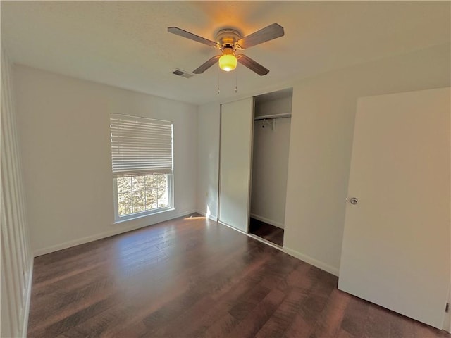 unfurnished bedroom featuring baseboards, a closet, visible vents, and wood finished floors