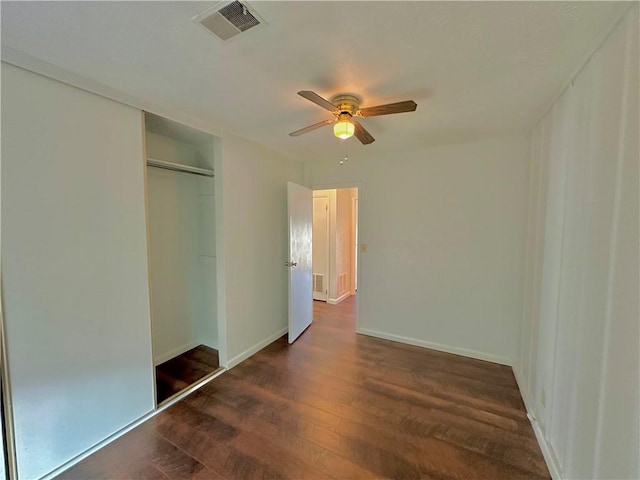 unfurnished bedroom with baseboards, visible vents, a ceiling fan, dark wood-type flooring, and a closet