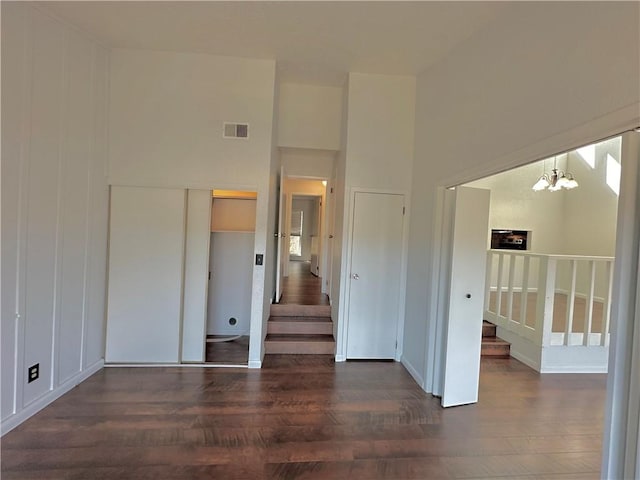 spare room with a notable chandelier, visible vents, stairway, and wood finished floors