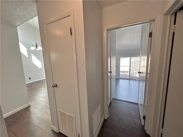 hallway with baseboards, dark wood finished floors, and a textured ceiling