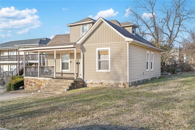 view of front of house with covered porch, a front lawn, and board and batten siding