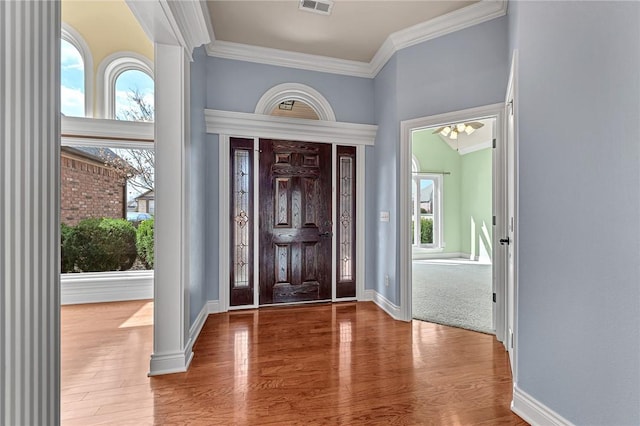 entryway with a wealth of natural light, crown molding, baseboards, and wood finished floors