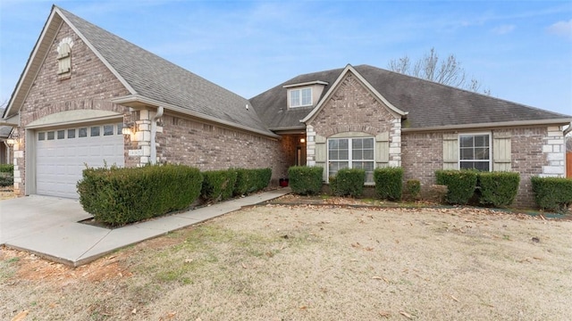 view of front facade with a garage, driveway, roof with shingles, and brick siding