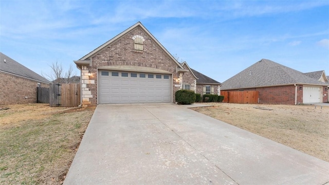 traditional-style house featuring brick siding, an attached garage, a gate, fence, and driveway