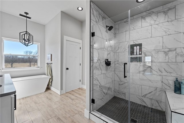 bathroom featuring a freestanding tub, a shower stall, baseboards, and an inviting chandelier