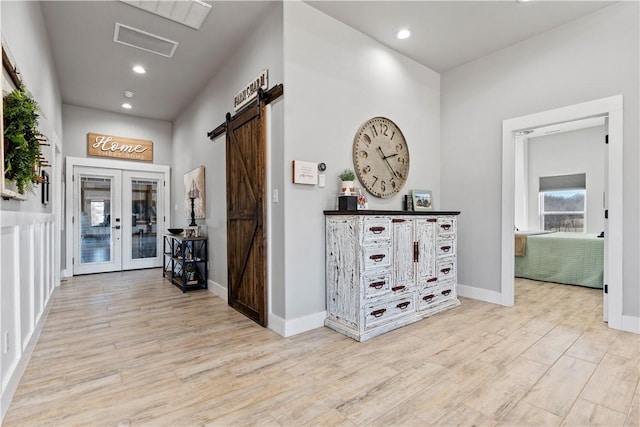 hall with a barn door, baseboards, wood finished floors, french doors, and recessed lighting