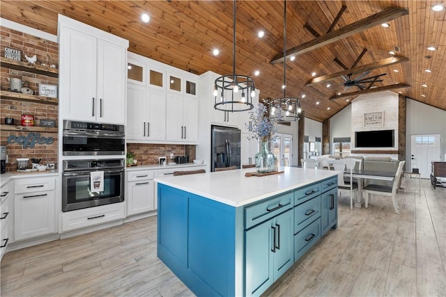 kitchen with high vaulted ceiling, stainless steel double oven, wood ceiling, blue cabinets, and black fridge