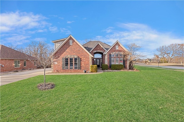 view of front of property featuring a front lawn, concrete driveway, and brick siding