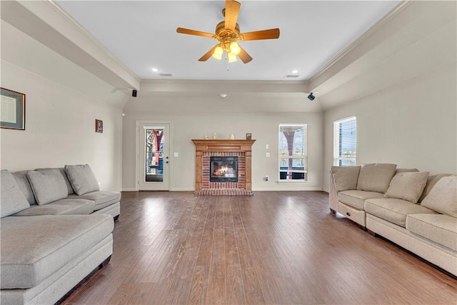 living area with visible vents, baseboards, a brick fireplace, dark wood finished floors, and crown molding