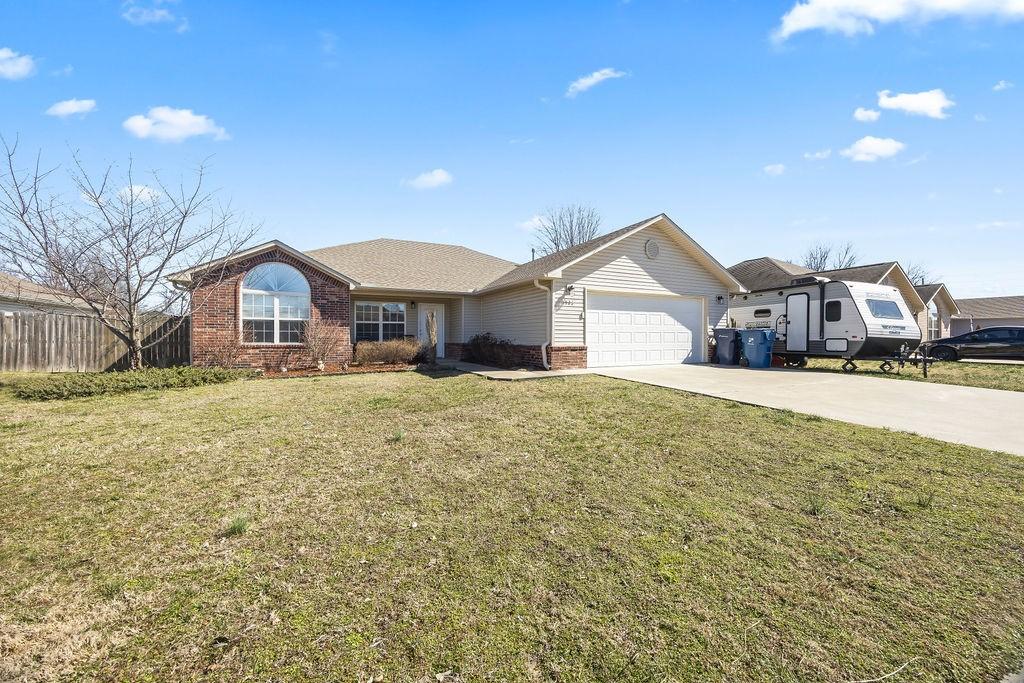 1523 William Ct, Siloam Springs, AR 72761 - single story home with a garage, driveway, brick siding, and a front lawn