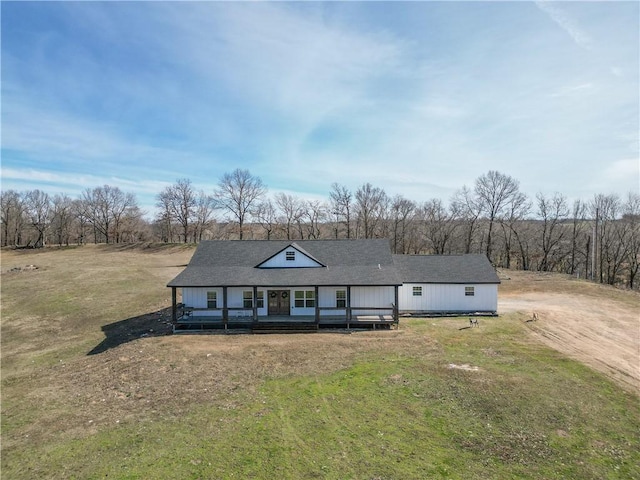 country-style home featuring roof with shingles and a front yard