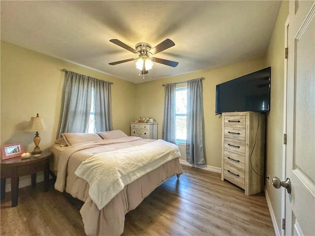 bedroom with a ceiling fan, baseboards, and wood finished floors