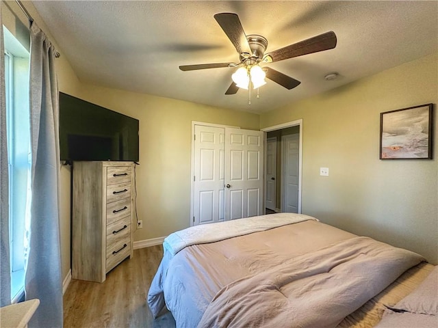 bedroom featuring a textured ceiling, baseboards, light wood-style flooring, and a ceiling fan