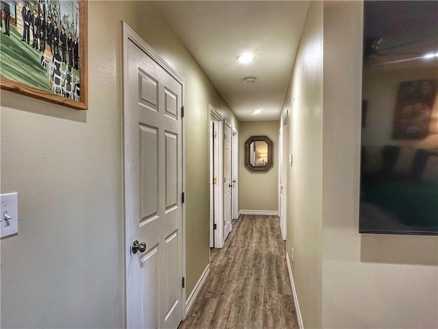 corridor featuring baseboards and wood finished floors