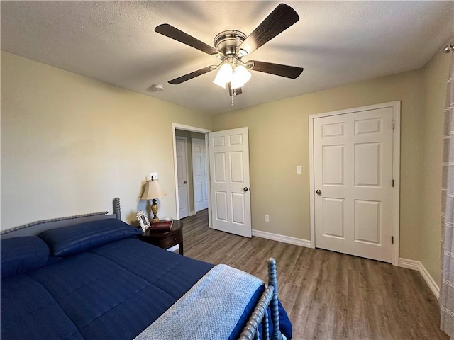 bedroom with a textured ceiling, wood finished floors, a ceiling fan, and baseboards