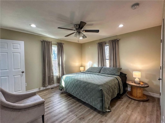 bedroom with multiple windows, baseboards, and wood finished floors