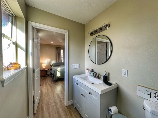 half bath featuring toilet, wood finished floors, and vanity