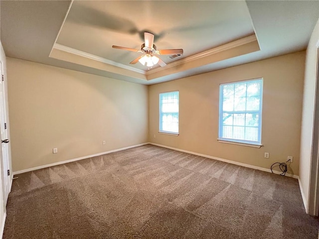 carpeted empty room featuring ceiling fan, ornamental molding, a raised ceiling, and baseboards