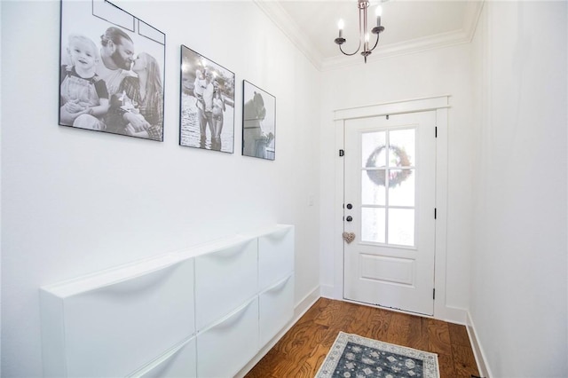 doorway featuring ornamental molding, dark wood-style flooring, an inviting chandelier, and baseboards