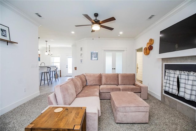 living room with baseboards, a fireplace, visible vents, and ornamental molding