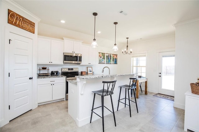 kitchen with appliances with stainless steel finishes, white cabinets, visible vents, and a kitchen bar