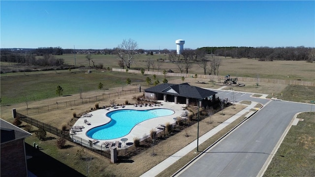 pool featuring a rural view, fence, and a patio