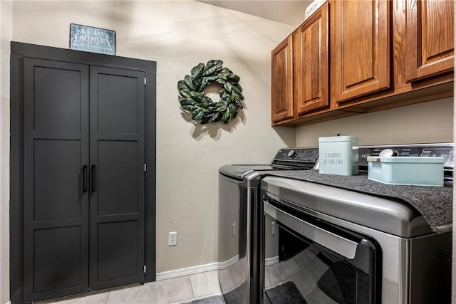 laundry room featuring separate washer and dryer, light tile patterned flooring, cabinet space, and baseboards