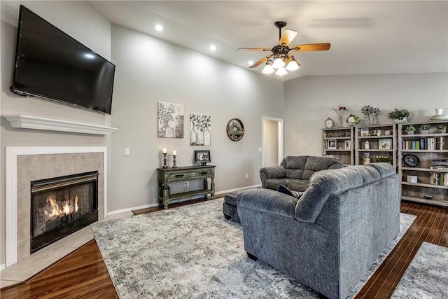 living room featuring a fireplace, ceiling fan, vaulted ceiling, wood finished floors, and baseboards