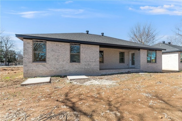 back of property with roof with shingles and brick siding