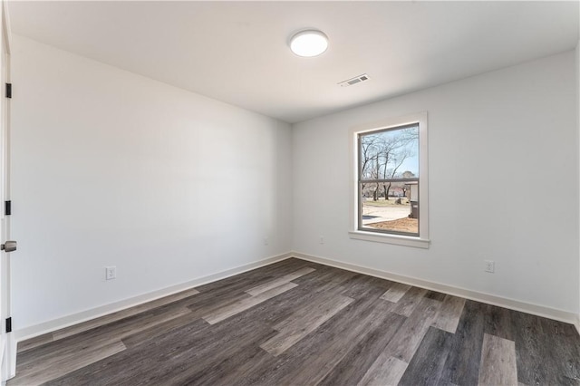 unfurnished room featuring dark wood-style flooring, visible vents, and baseboards