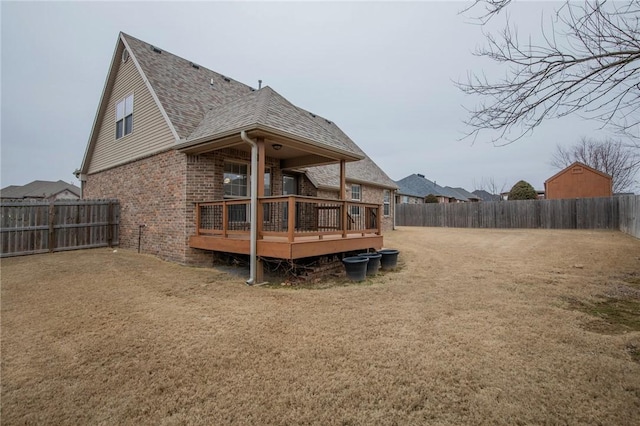 rear view of property featuring a shingled roof, brick siding, a fenced backyard, and a wooden deck