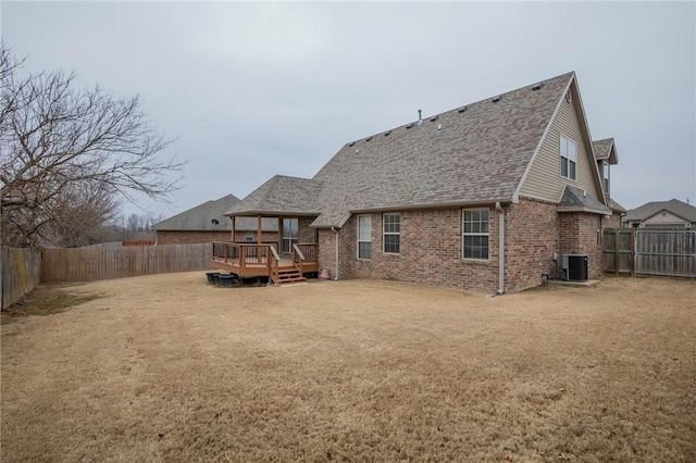 rear view of property featuring brick siding, a fenced backyard, a wooden deck, and central AC unit