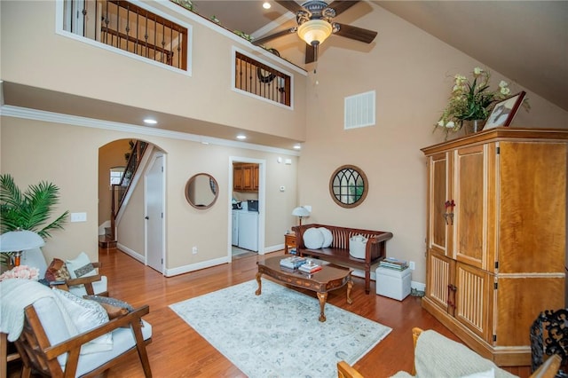 living room featuring arched walkways, visible vents, ceiling fan, wood finished floors, and baseboards