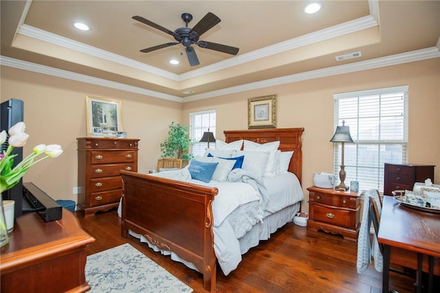 bedroom with dark wood-type flooring, a raised ceiling, visible vents, and crown molding